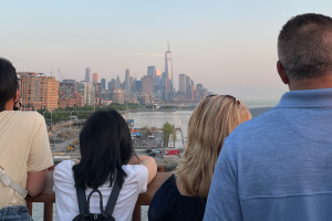 Small private tour group facing away gazing at Manhattan skyline and One World Trade